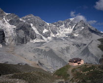 Sulden. A single pink building at the foot of Schaubachhutte with Mount Zebru and Ortler