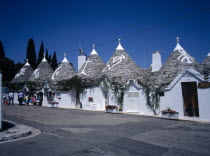 White Trulli buildings with runic symbols painted on the grey stone roofs in Alberobello village that have been converted into houses and a shop. No mortar is used  although the interior is plastered.