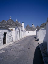 White Trulli buildings with grey stone roofs in Alberobello village that have been converted into houses. No mortar is used  although the interior is plastered.