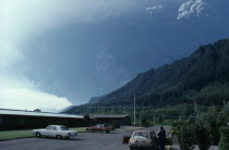 Mount St Helens Volcanic eruption 1980 at 8.40am. View from car park with a person standing outside a car looking towards forest covered mountain with billowing ash rising       In 1982 the President...