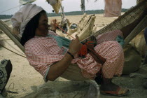 Wayuu woman sews a coloured  faja  / woven woollen belt for her husband sitting in a fique / cactus fibre hammock in their scanty desert shelter  Indigenous Tribes American Colombian Colored Fiber So...