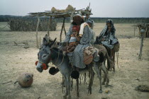 Mother and daughters on donkeys  normal means of transport in Guajira. Mother protects face from strong sun and salty winds with mixture of burnt fungi and goat fat. Note fired clay water vessel on gr...