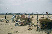 Portete a coastal desert settlement.  Wayuu encampment consisting of shelters of hardwood poles and old sacks. Women sewing inside central shelter.Indigenous Tribes American South America  Hispanic I...
