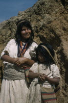 Portrait of two sisters  both wearing typical woven cotton garments.  Elder sister with many stranded waist belt and necklace of coloured glass beads  a sign of wealth. Younger sister with  fique  / c...