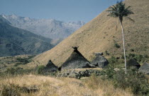 Religious centre of Takina where very young boys are trained to become  mamas  / priests. Racks of sacred potsherds at apex of each  nuhue  / temple roof. Lesser peaks of Sierra Nevada in backgroundI...