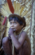 Young boy playing panpipes outside maloca prior to a festival. Painted with deep purple we leaf dye and wearing crown of red macaw and yellow toucan feathersTukano / Makuna      Indigenous Tribes  ri...
