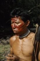 Hunter with red  karajuru  / facial paint  wooden ear plug and white glass bead necklace  carrying coca powder pouch with bone pipe  coca sustains whilst hunting. Hard  macana  wood bow and quiver of...
