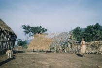 Woman walks towards large dwelling house with roof under constructionIndigenous Tribes Colombian / Venezuelan Border Area American Colombian Kids South America Columbia Hispanic Indegent Latin Americ...