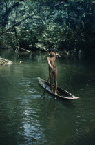 Boy paddles canoe along tributary stream through dense tropical jungle. Wearing intricately made silver earplugs as adornment  to attract girlsThe Noanama are a minority group of approximately 3000...