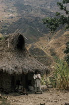 Young man stands outside the family home above Takina  wearing typical woven cotton manta / cloak and trousers with crossed  mochilas   / shoulder bags of  fique  cactus fibre.Indigenous TribesCarib...