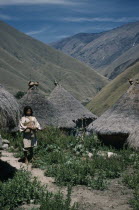 San Miguel village. A young  mama  / priest stands in pathway leading  to thatched dwellings and ritual centres  with sacred pots at roof apices.Indigenous TribesCaribbean coast of Colombia. American Colombian South America West Indies Columbia Hispanic Indegent Latin America Latino Scenic
