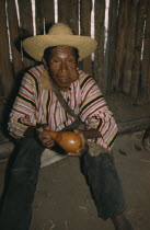 Marty  an old man  wearing a local peasant straw hat and Indian woven striped  manta   / cloak. Chewing a wad of coca leaves  holding a gourd for lime powder  the catalyst for coca  which releases a v...