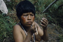 Girl applying bright red  ochote  facial paint extracted from ground ochote seeds. Indigenous TribesAmerican Colombian South America Columbia Hispanic Indegent Latin America Latino