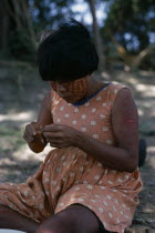 rio Meta "Tree Camp". Cuiva woman  Yanakwas wife  wearing traded flower print dress with red ochote/facial paint She threads coloured glass beads obtained from boats which ply the rivers of the Llanos...
