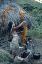 Mama/priest Valencias wife rinses fique/cactus fibre in root dye in a hollowed timber trough to use for banded design on mochilas/ shoulder bags  such a mochila strung from her forehead She and baby d...