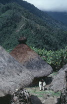 Old traditional centre of Chendukua Two mamas/priests talk and ceremonially greet each other by exchanging coca leaves  outside old nuhue/temple with conical thatched roof & sacred potsherds in rack a...