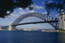 The Harbour Bridge framed by silhouetted trees.