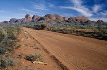 A dirt road through the park  with Katatjuta  The Olgas  in the background.