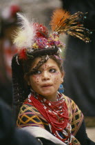 A young Kalash girl in traditional dress at the Chilimjusht Festival. Decorated face  lots of beaded necklaces and earrings.