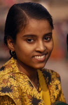 Young girl on the ghats wearing a yellow shirt with a nose stud and earrings.