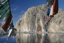 Carved Buddha  Buddhist paintings and prayer flags on a rock wall by the road from Lhasa to the airport.