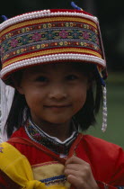 Near Kunming. Portrait of a young Sani girl at the Stone Forest  wearing a decorated hat with bead trim.