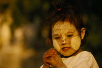 A young girl near Bupaya Pagoda  with white painted face  circles on her cheeks. Burma