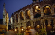 Teatro Romano.  Exterior facade of ruined theatre built in the 1st century BC illuminated at night with passers by in blur of movement in foreground. Theater