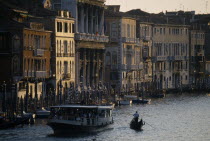 Crowded vaporetto or waterbus and gondola on the Grand Canal near Rialto Bridge.