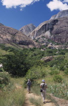 A tourist being lead by a guide towards rocky mountains and trees in the Anjaha Nature Reserve  Anja
