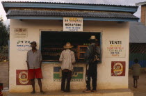 Men standing at a kiosk which sells rum and beer