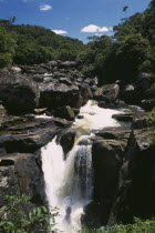 Waterfalls cascading over rocks surrounded by lush green tropical rainforest