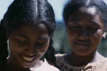 Road to Ranomanfana. Portrait of two young women smiling with their eyes looking down one girl with plaited pig tails