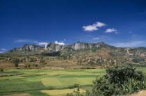 Road to Ambalavao.  View across green paddy fields towards a village of thatched huts set into hillside