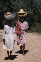 Near Ambositra. Two barefooted women walking up a dirt track carrying wicker baskets on their heads