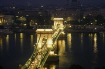 Bridge of Chains over the River Danube illuminated at night with lights from crossing traffic.