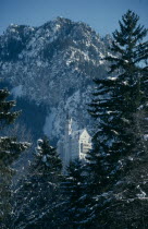 Castle built on rock ledge over the Pollat Gorge near Fussen in the Bavarian Alps in snowy mountain and pine forest landscape.