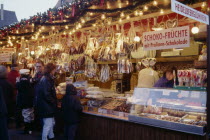 Customers at decorated stall in Christmas market selling iced biscuits  sweets and cakes. Bavaria
