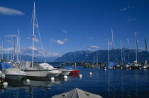 Boats moored in marina with view across Lake Geneva beyond.