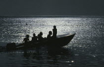 People traveling on a motorboat at night silhouetted against the light of the moon