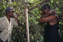 Man drinking water and a woman washing under a shower from a aqueduct outside their home