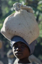 Portrait of a young girl carrying a full sack on her head