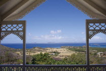 View from a carved Villa balcony over land and trees towards the coastline
