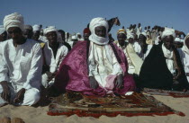 Muslim chief at prayer during festival surrounded by crowd. Moslem