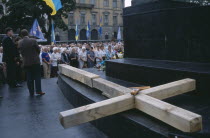 A large wooden cross lays flat in front of a crowd  dedicated to the Gulag victims  Lviv forced labour camp