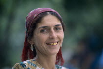 Portrait of a woman with a dark red head scarf  earrings and gold teeth