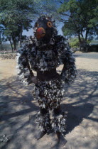 Makishi masked dancer wearing feathered bird costume.