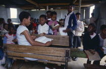 Female looking at exercise books of children in school classroom. Kwazulu Natal
