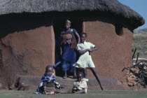 Mother and children in doorway of thatched  mud brick home.family