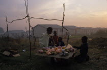 Women and children selling fruit from makeshift stall in township.